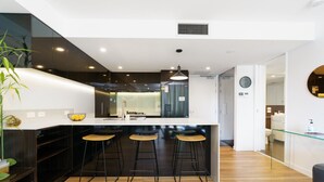 A modern kitchen with a central island, bar stools, and a large window. - Quiet Modern Apartment in Prime Location (Reid)