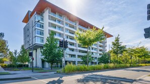 A multi-story building with a modern architectural design, featuring balconies and large windows. - Quiet Modern Apartment in Prime Location (Reid)
