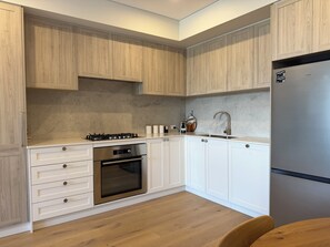 Une cuisine moderne avec des armoires en bois, un réfrigérateur en acier inoxydable, un four encastré et une cuisinière à gaz.