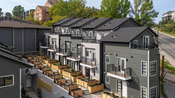 Ein modernes Mehrfamilienhaus mit mehreren Wohnungen, Balkonen und Holzpflanzgefäßen.