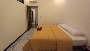 A small, neatly arranged bedroom with a bed, a bedside table, and a window. - Rumah WJ Room and Suites (Pecatu)