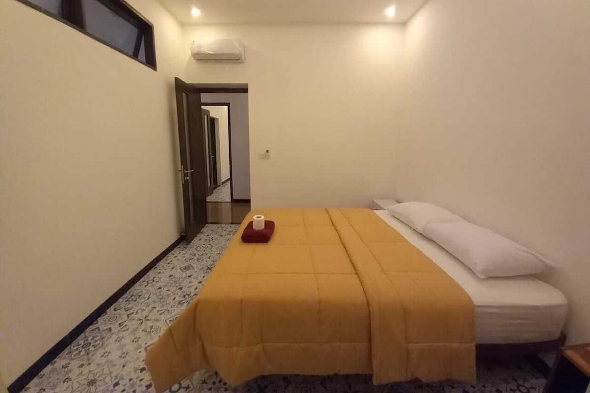 Un dormitorio pequeño y ordenado con cama, mesita de noche y ventana.