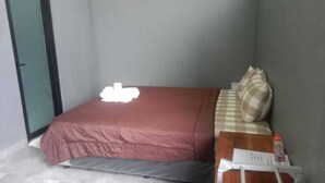 A small, neatly made bed with a red bedspread and a checkered pillow. A water bottle and a piece of paper are on the side of the bed. - Rumah WJ Room and Suites (Pecatu)
