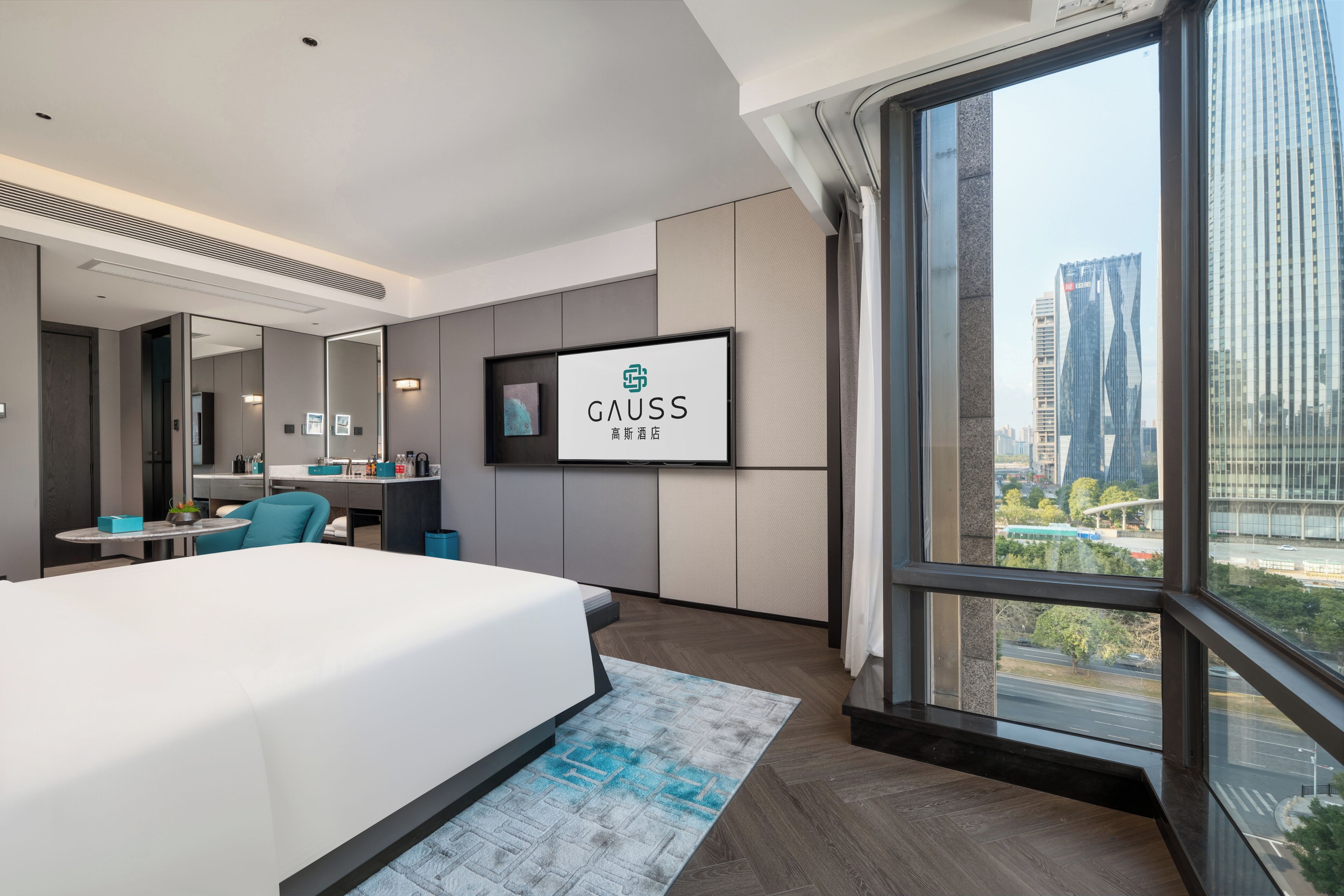 A modern hotel room with a large bed, a desk, a TV, and a city view.