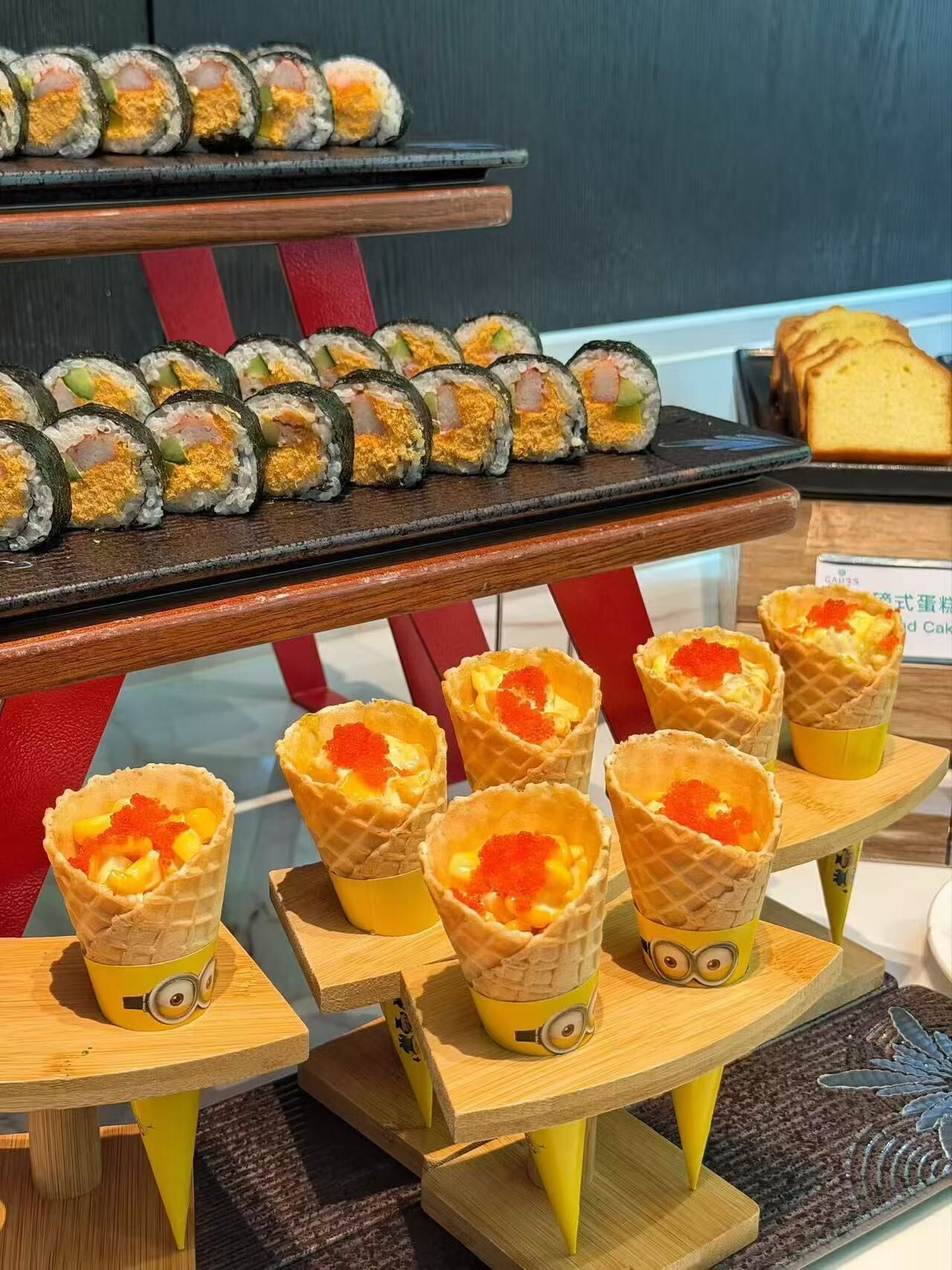 A dessert display with sushi rolls and waffle cups topped with red caviar.