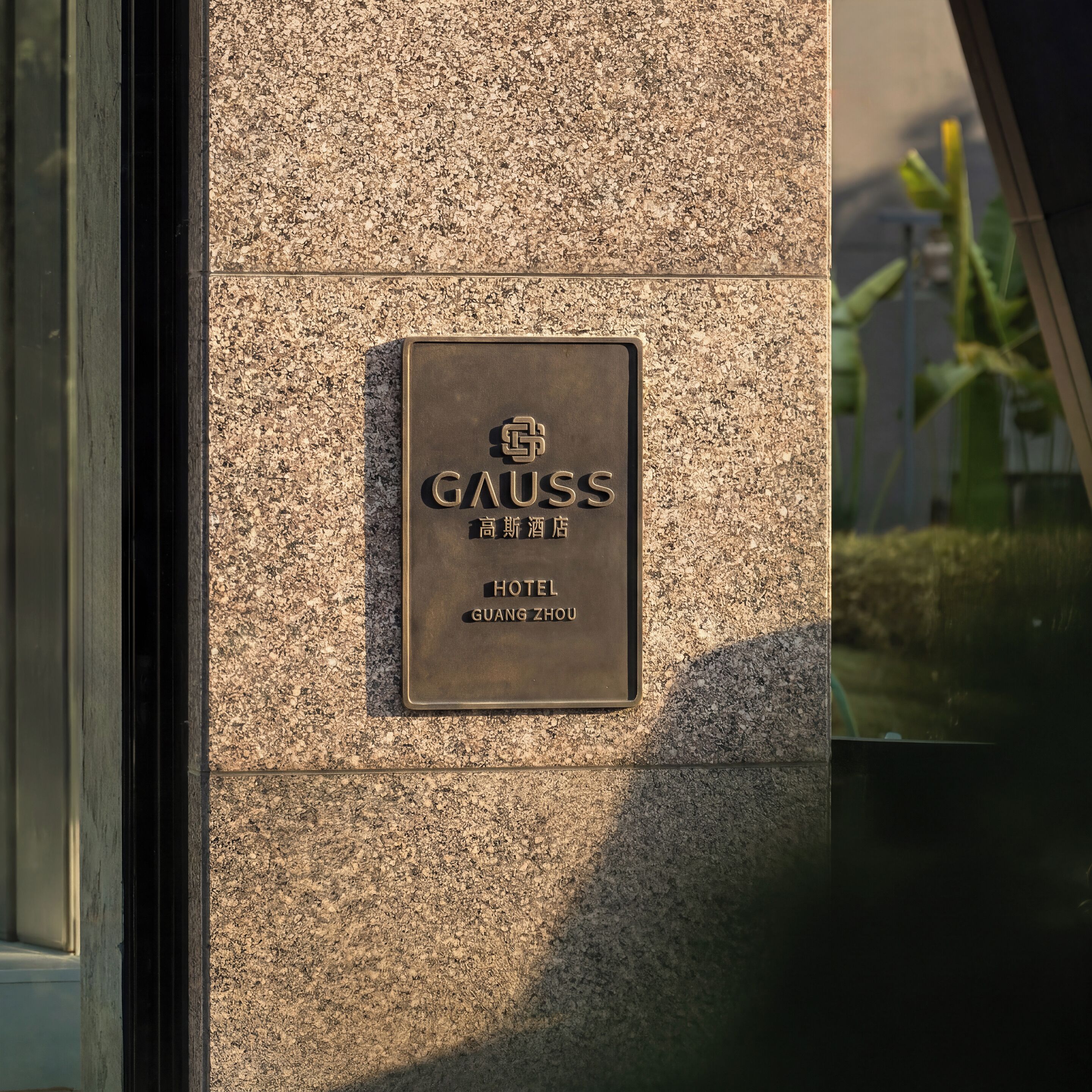 A plaque on a textured wall with the name 'GAUSS HOTEL' and 'GUANG ZHOU' in both English and Chinese.