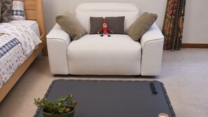 En hvid sofa med en lille elveplys, et sort bakkebord og en grøn plante.