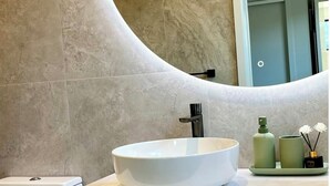A bathroom with a white vessel sink, a mirror, and a toilet. - Lovely one-bedroom apartment with AC and stunning mountain views in Jacks Point (Jack's Point)