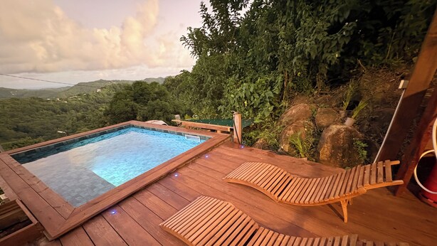 En træterrasse med jacuzzi og liggestole med udsigt over et bjerglandskab.