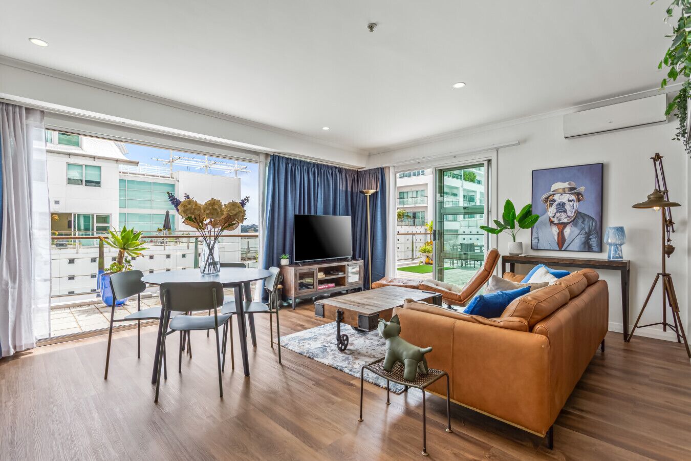 Een moderne woonkamer met een bank, televisie en een eethoek.