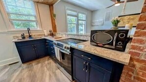 Une cuisine avec des meubles de couleur sombre, un plan de travail en granit, une cuisinière et un four à micro-ondes.