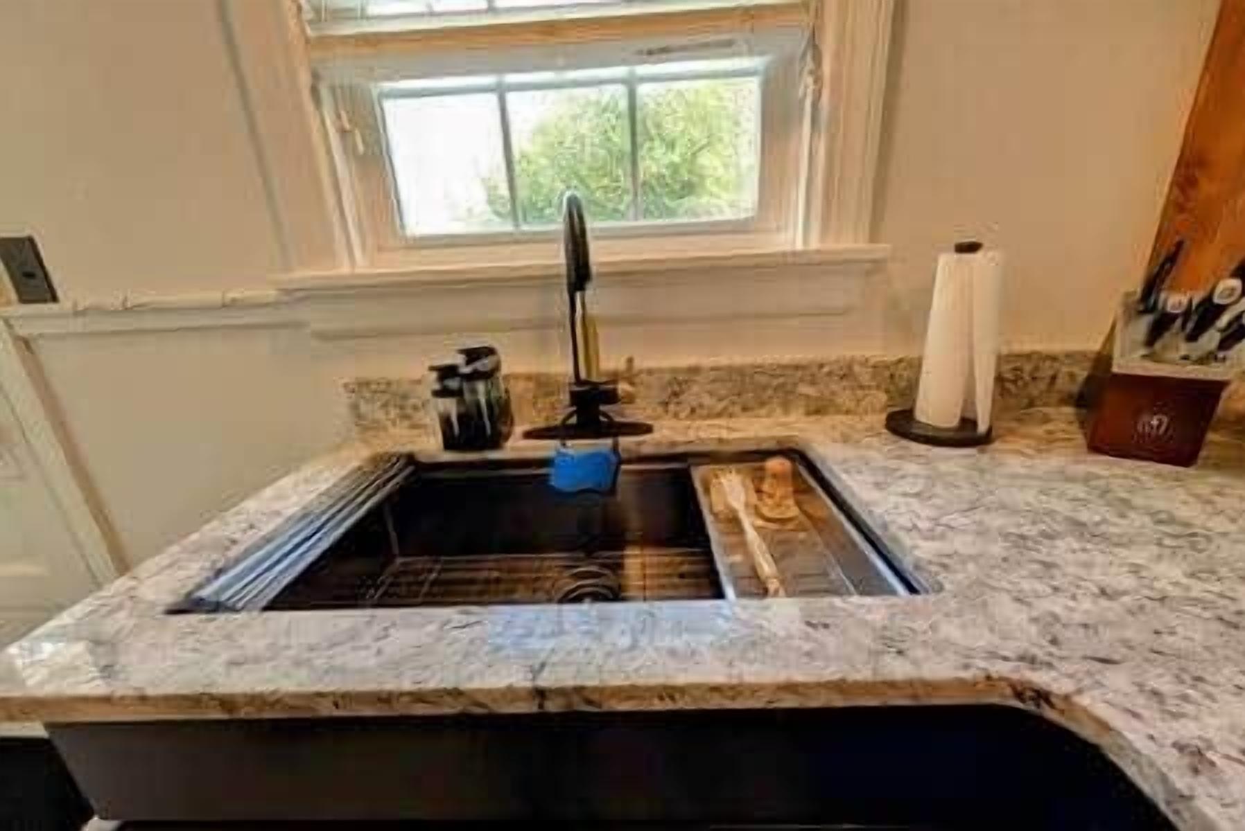 A kitchen with a granite countertop, a stainless steel sink, and a window above the sink.