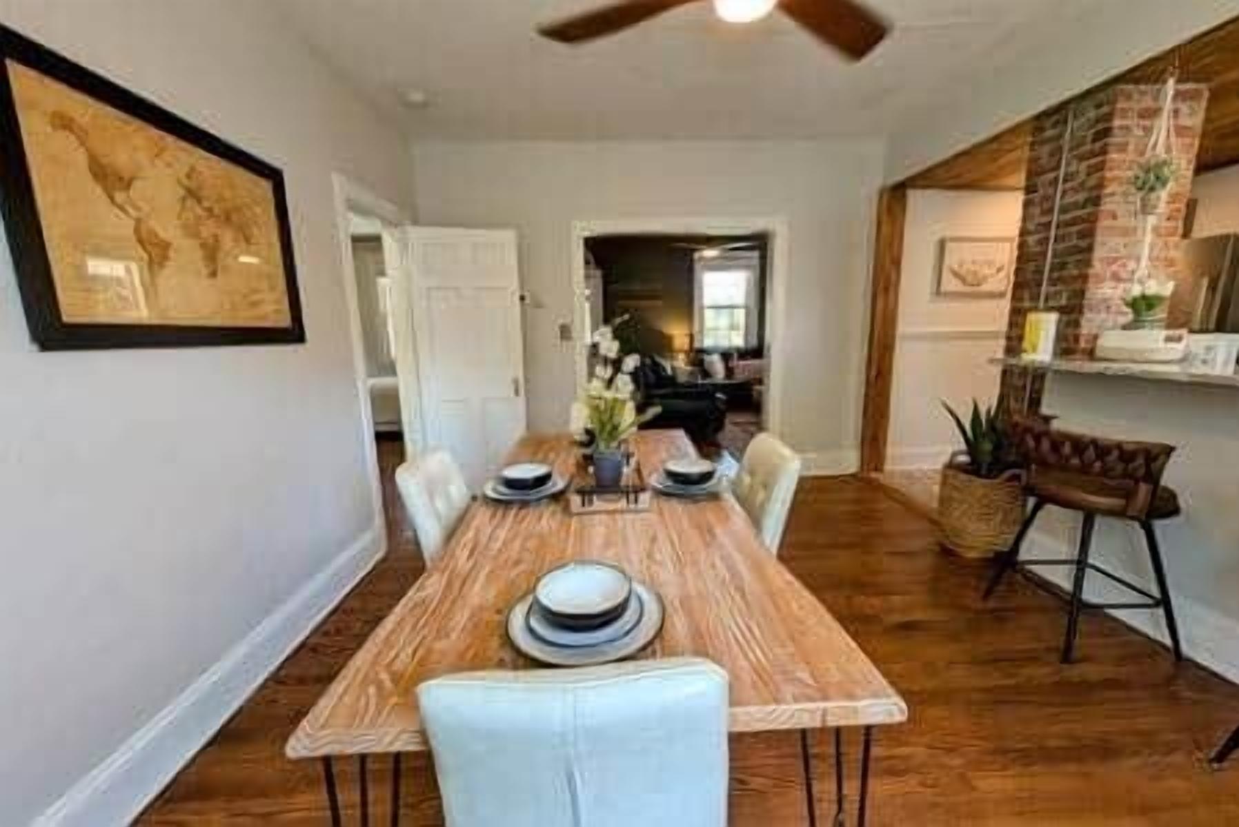 A dining area with a wooden table, white chairs, and a ceiling fan.