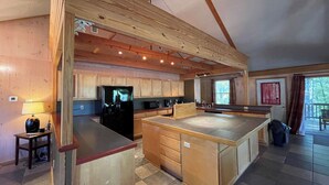 A spacious kitchen with wooden cabinets, a central island, and a built-in refrigerator. - Relax & Unwind in this Vaulted-Ceiling Cabin with Fireplace, Full Kitchen & Lake Views (Zwolle)
