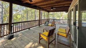 A wooden deck with a railing, a ceiling fan, and two chairs with yellow cushions. - Relax & Unwind in this Vaulted-Ceiling Cabin with Fireplace, Full Kitchen & Lake Views (Zwolle)