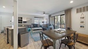 A modern kitchen with a built-in oven, a refrigerator, and a dining area with a wooden table and chairs. - Fully renovated 2BR/2BA within walking distance to the beach and so much to do! (Hilton Head Island)
