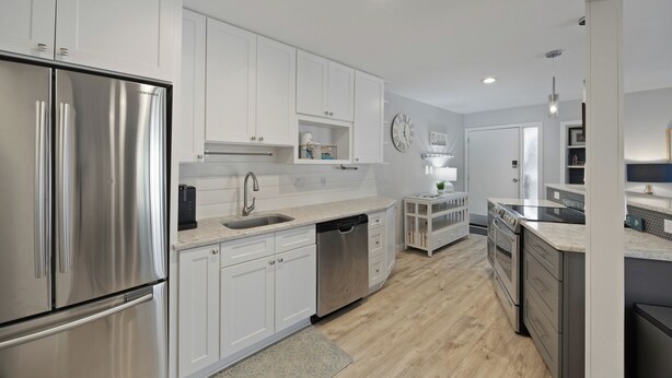 A modern kitchen with stainless steel appliances, white cabinetry, and a wooden floor. - Fully renovated 2BR/2BA within walking distance to the beach and so much to do! (Hilton Head Island)