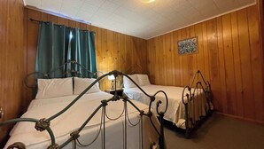 A room with two beds, wooden walls, a ceiling light, and a painting. - Comfortable 3-Bedroom Retreat with Fireplace, Full Kitchen & Outdoor Firepit (Zwolle)