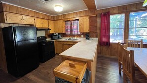 A kitchen with wooden cabinets, a black refrigerator, a microwave, and a coffee maker. - Comfortable 3-Bedroom Retreat with Fireplace, Full Kitchen & Outdoor Firepit (Zwolle)