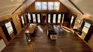 Une pièce spacieuse de style loft, avec un plafond haut, des murs en bois et de grandes fenêtres.
