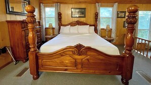 Una cama con dosel de madera, un tocador con espejo y una ventana con cortinas.