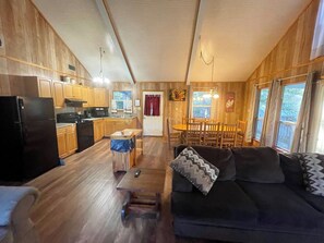 A wooden cabin interior with a kitchen, dining area, and living room. - Charming 2-Bedroom Cabin with Full Kitchen, Vaulted Ceiling & Lake Views (Zwolle)