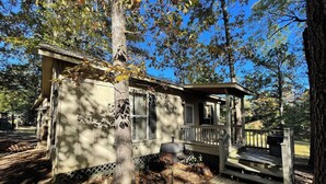 A small cabin with a porch, a chimney, and a deck. - Vaulted-Ceiling Cabin for 4 with King Bed + Bunks, Full Kitchen & Pond Views (Zwolle)