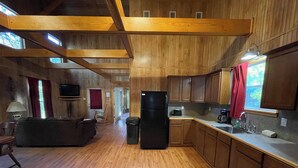 A spacious kitchen with wooden cabinets, a refrigerator, and a dining area with a table and chairs. - Spacious 1-Bedroom Cabin with Full Kitchen, Vaulted Ceiling & Outdoor Space (Zwolle)