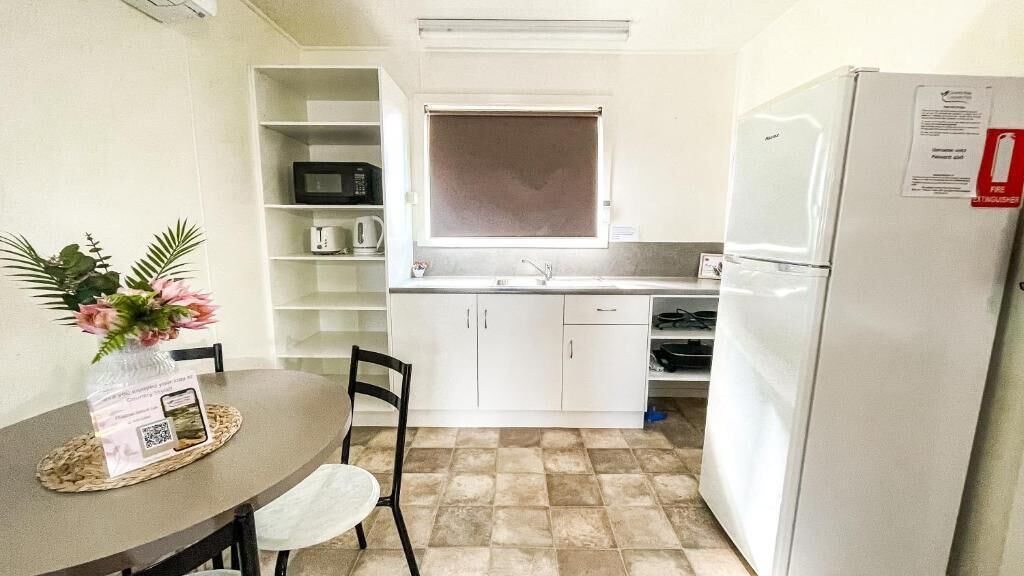 A compact kitchen with white cabinets, a microwave, a sink, and a refrigerator.