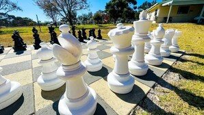 A large outdoor chessboard with oversized chess pieces. - Country Style Holiday Park (Glen Aplin)