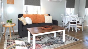 A modern living room with a sofa, coffee table, and dining area. - Country Style Holiday Park (Glen Aplin)