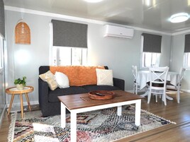 A modern living room with a sofa, coffee table, and dining area.