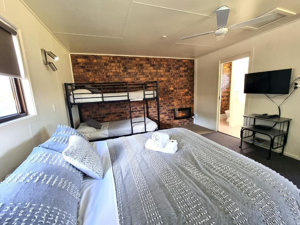 A room with bunk beds, a flat-screen TV, and a brick wall.