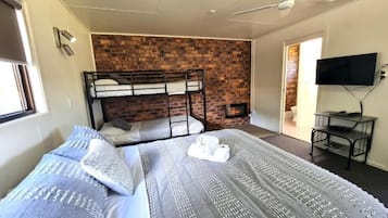 A room with bunk beds, a flat-screen TV, and a brick wall.