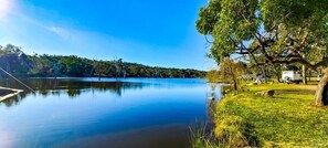 A calm lake with a dock, surrounded by grassy areas and trees. - Country Style Holiday Park (Glen Aplin)