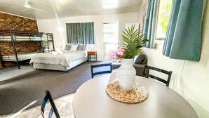 A room with bunk beds, a round table with a vase, and a potted plant. - Country Style Holiday Park (Glen Aplin)