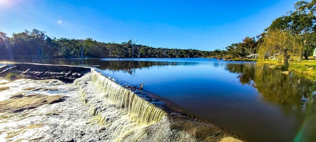 Un lac paisible, avec un barrage en béton et des arbres en arrière-plan.