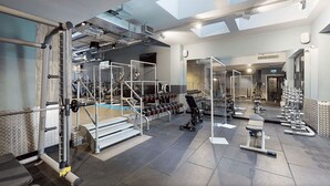 Un gimnasio con equipo de levantamiento de pesas, cintas de correr y un espejo grande.