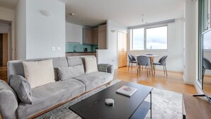 Een moderne woonkamer met een grijze bank, een salontafel en een eetgedeelte met stoelen en een tafel.