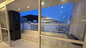 A modern interior with a glass partition, a marble column, and a balcony with a white railing. - Copacabana 4 bedrooms (2 suites) with side sea and mountain views (Rio de Janeiro)