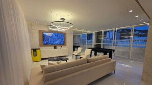 A modern living room with a sofa, a TV, a pool table, and a balcony with a view. - Copacabana 4 bedrooms (2 suites) with side sea and mountain views (Rio de Janeiro)