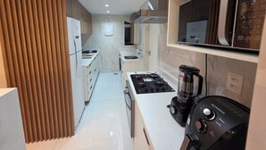 A modern kitchen with a gas stove, a blender, and a microwave. - Copacabana 4 bedrooms (2 suites) with side sea and mountain views (Rio de Janeiro)