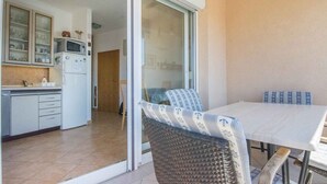 A kitchen with a microwave, refrigerator, and cabinets. There is a dining area with a table and chairs. - Holiday apartment with balcony (Biograd na Moru)