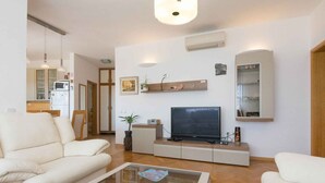 A modern living room with a sofa, coffee table, TV, and built-in shelves. - Holiday apartment with balcony (Biograd na Moru)