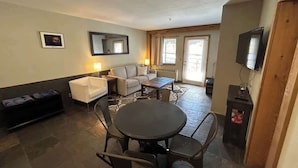 Un espacio habitable compacto con una mesa de comedor redonda, un sofá, un televisor y un mueble auxiliar pequeño.