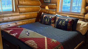 A log cabin bedroom with a bed, quilt, and two windows with blinds. - Wilderness, wildlife, and fishing cabin - The Ponderosa at Alta Ranch (Darby)