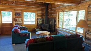 A log cabin interior with a sofa, armchair, and a small round table. - Wilderness, wildlife, and fishing cabin - The Ponderosa at Alta Ranch (Darby)