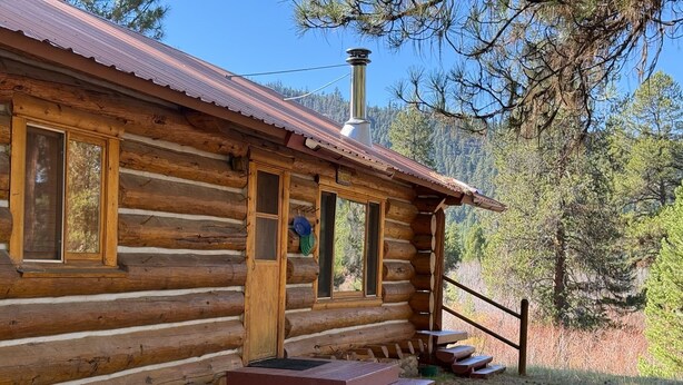 A log cabin with a chimney, wooden steps, and a metal railing. - Wilderness, wildlife, and fishing cabin - The Ponderosa at Alta Ranch (Darby)