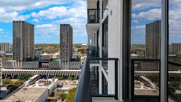 A high-rise building with a modern architectural design, featuring a balcony with a glass railing and a view of the cityscape. - Crosby 31 | Signature Skyline Residence (Miami)
