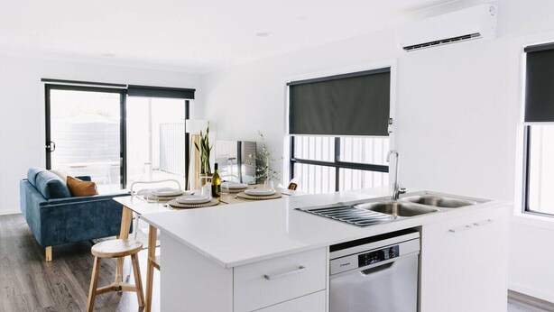Une cuisine moderne dotée d’un îlot central, de meubles blancs et d’un lave-vaisselle encastré.